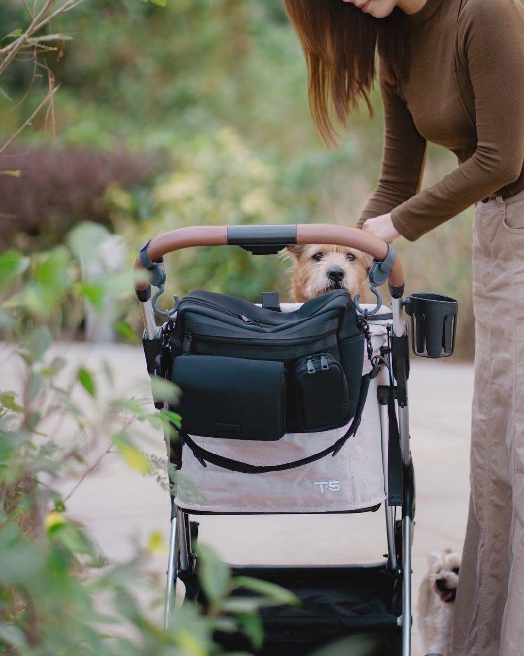 Person pushing a stroller with a dog inside, with a stroller bag